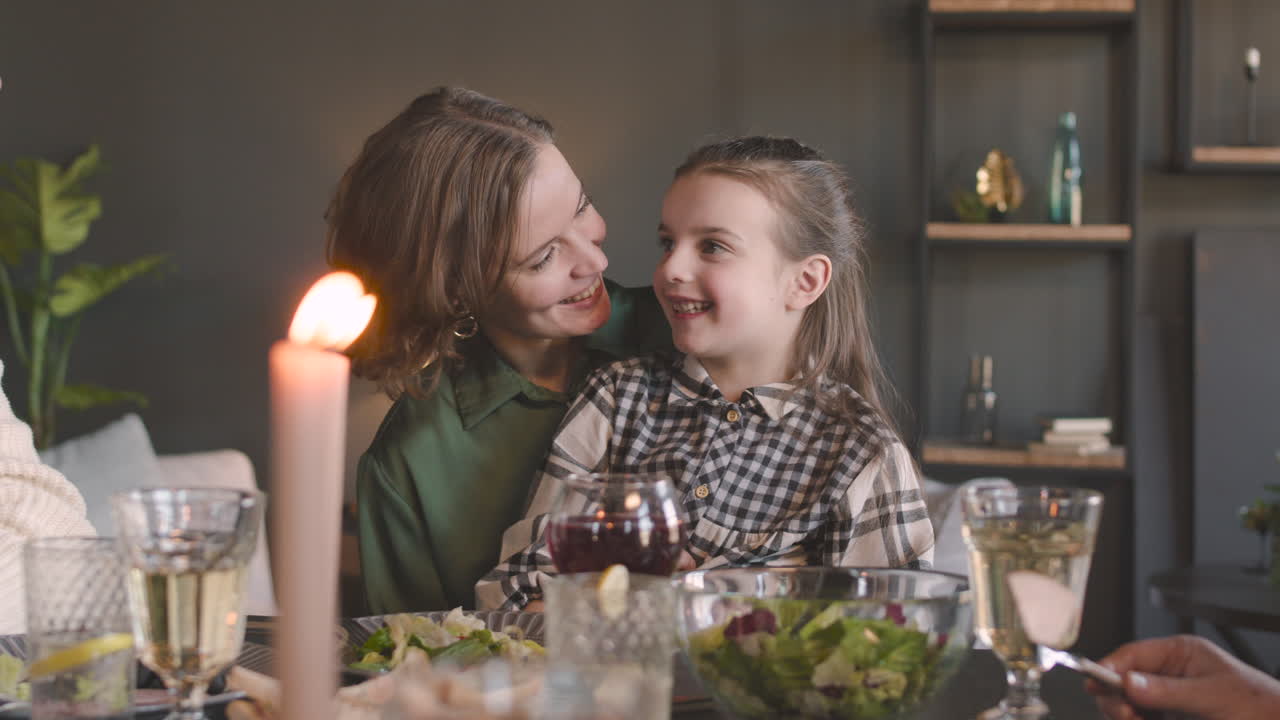 Loving Woman And Shy Little Girl Talking Together While Sitting At Dinner Table During A Family Meal