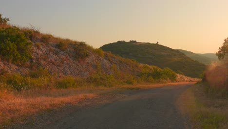 countryside sunset with this captivating video. the golden light bathes a winding road as it disappears into the horizon, surrounded by rolling hills and natural landscape