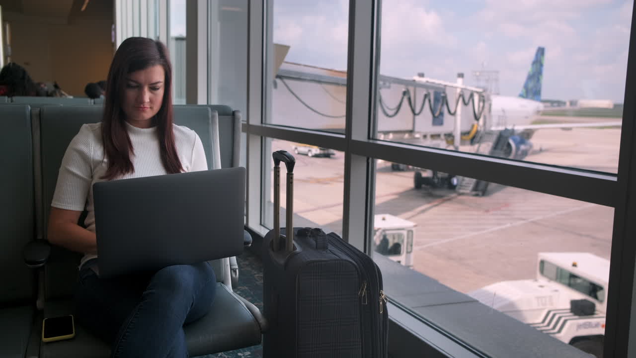 una joven atractiva usa una laptop en la terminal del aeropuerto