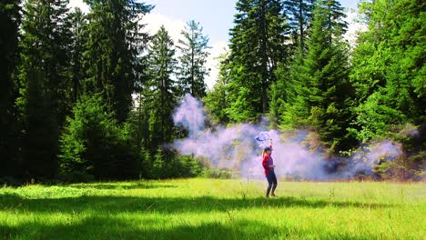 slowmo, young woman holding purple smoke bomb runs and spins around in a forest meadow