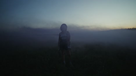 woman in a field shrouded in fog at sunset