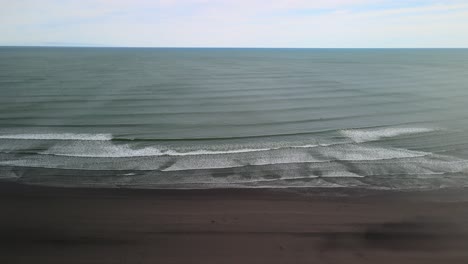 Wide-angle-landscape-aerial-video-over-black-sand-beach