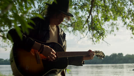 man playing acoustic guitar by the river