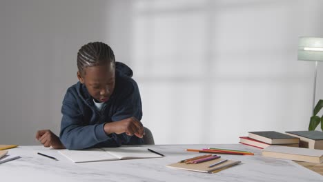 studio shot of boy at table struggling to concentrate on school book 1