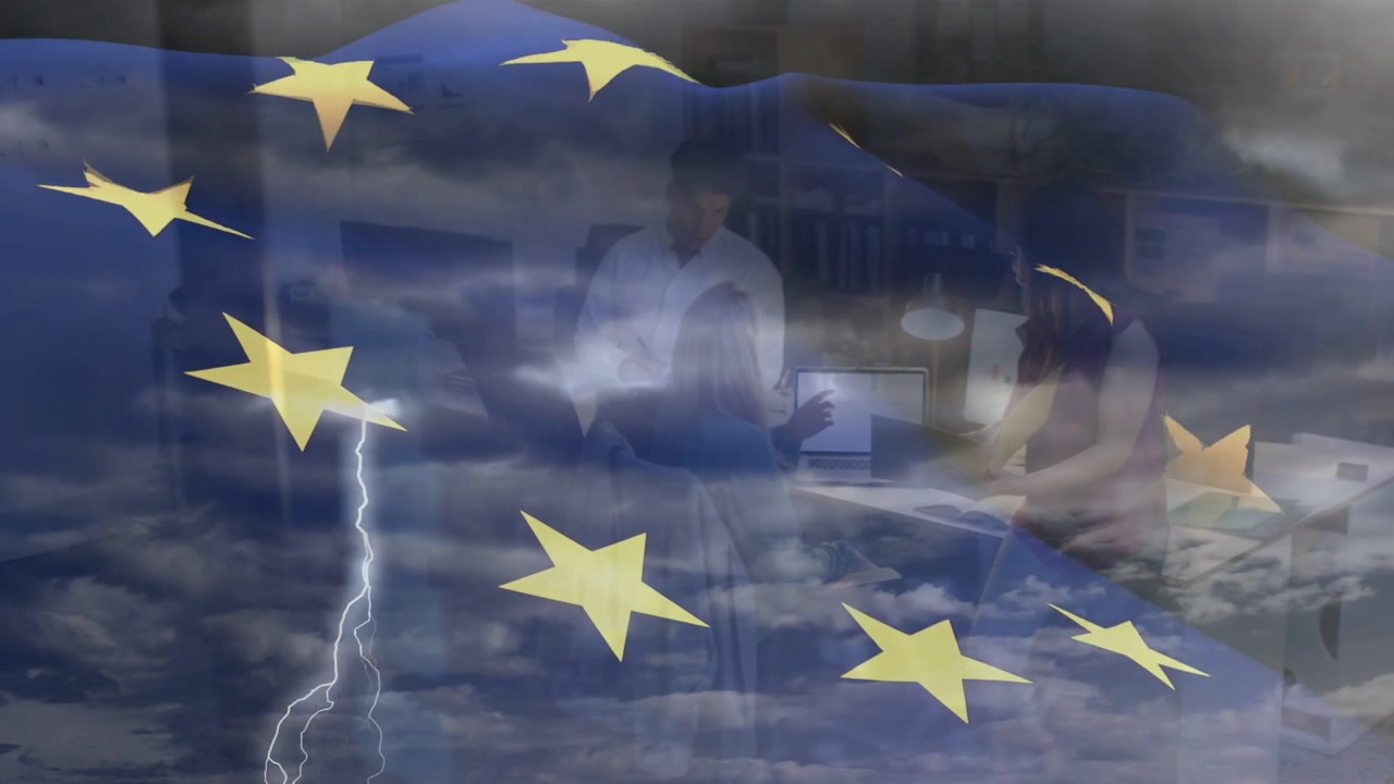 Team che si china verso il monitor e revisiona documenti aziendali con una sovrapposizione animata della bandiera dell'UE che appare.