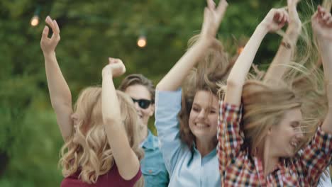 happy friends dancing, having fun and enjoying party outdoors.