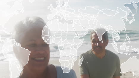 senior couple walking together on sandy beach, showcasing global map overlay for business growth