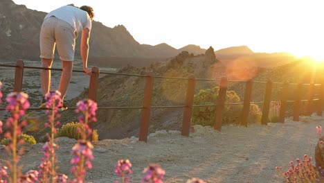 young man climbing over guardrail in teide national park, dangerous