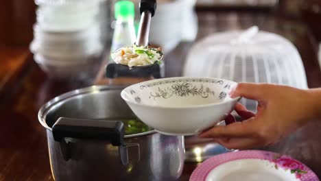 person ladling boiled rice into a bowl