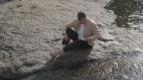 paper boat on river. origami ship sailing on pond. man hand launch paper boat on water and pushing it away. handsome man launching origami ship in water.