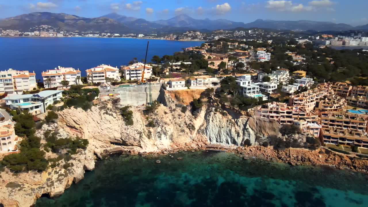 Discover the stunning coastline of Santa Ponsa in Mallorca. This captivating view showcases beautiful cliffs, clear blue waters, and luxurious villas nestled along the shore under a bright sky.