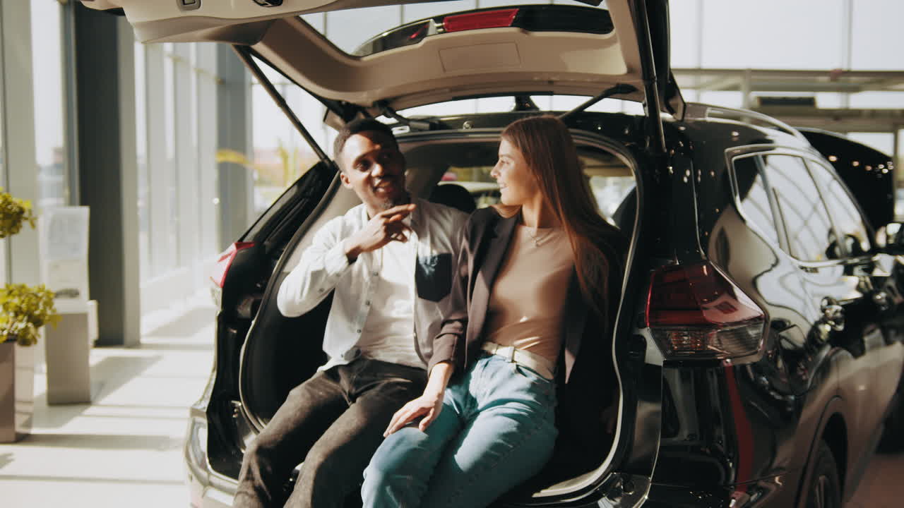 una pareja mirando el interior de un coche nuevo en una sala de exposiciones