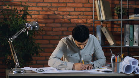 arabian businessman working as a designer or architect while drawing something with a pencil and rule on the table in his office