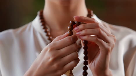 person's hands holding and counting prayer beads