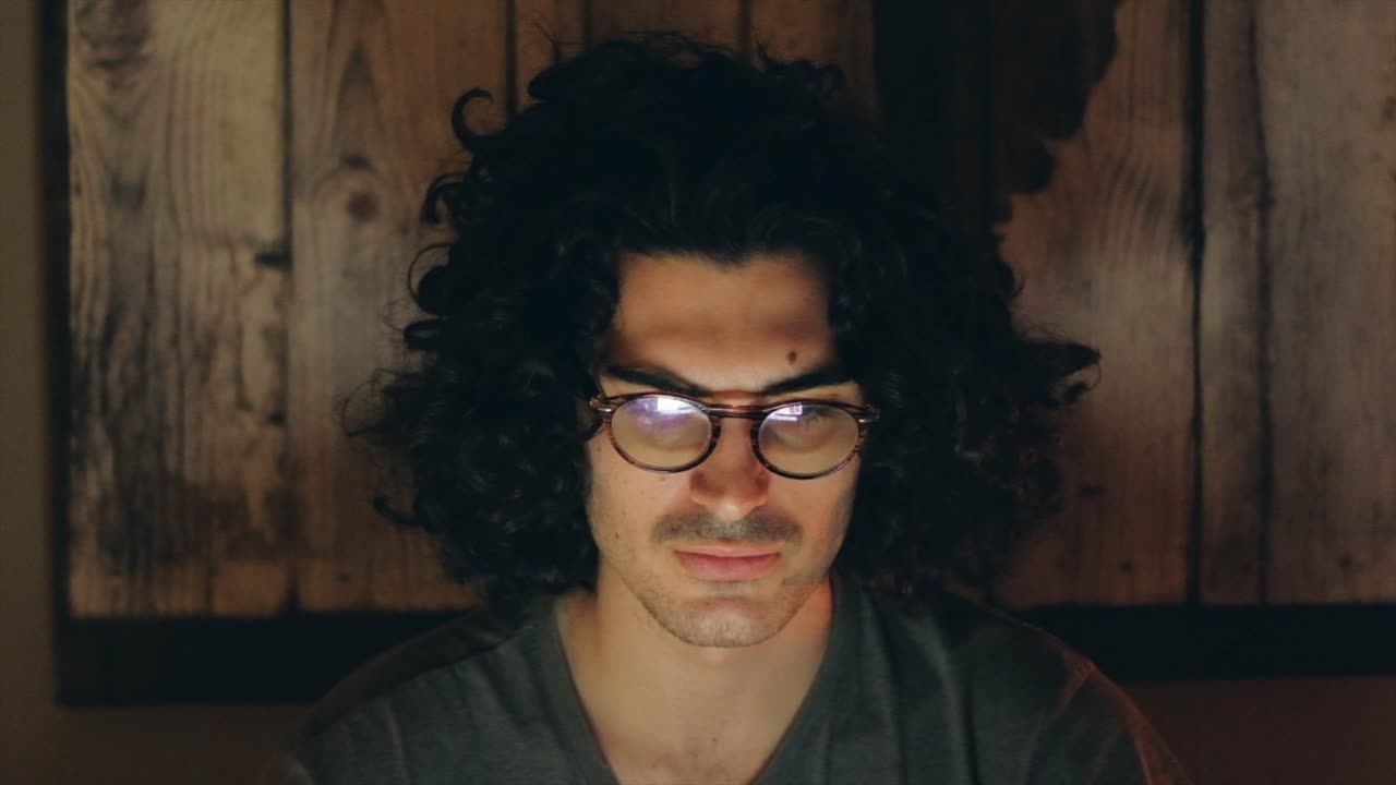 Focused Man with Curly Hair Nodding While Reading Deep in Though on Screen in Slow Motion