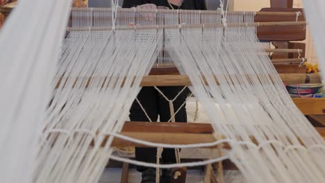 las partes móviles de un telar tradicional mientras una mujer teje tela.
