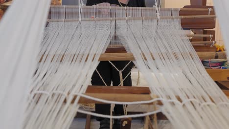 the moving parts of a traditional loom as a woman weaves fabric