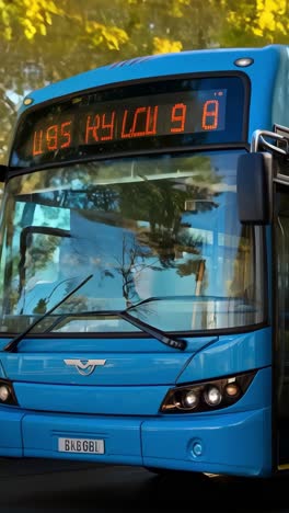 blue city bus driving through urban park on a sunny afternoon