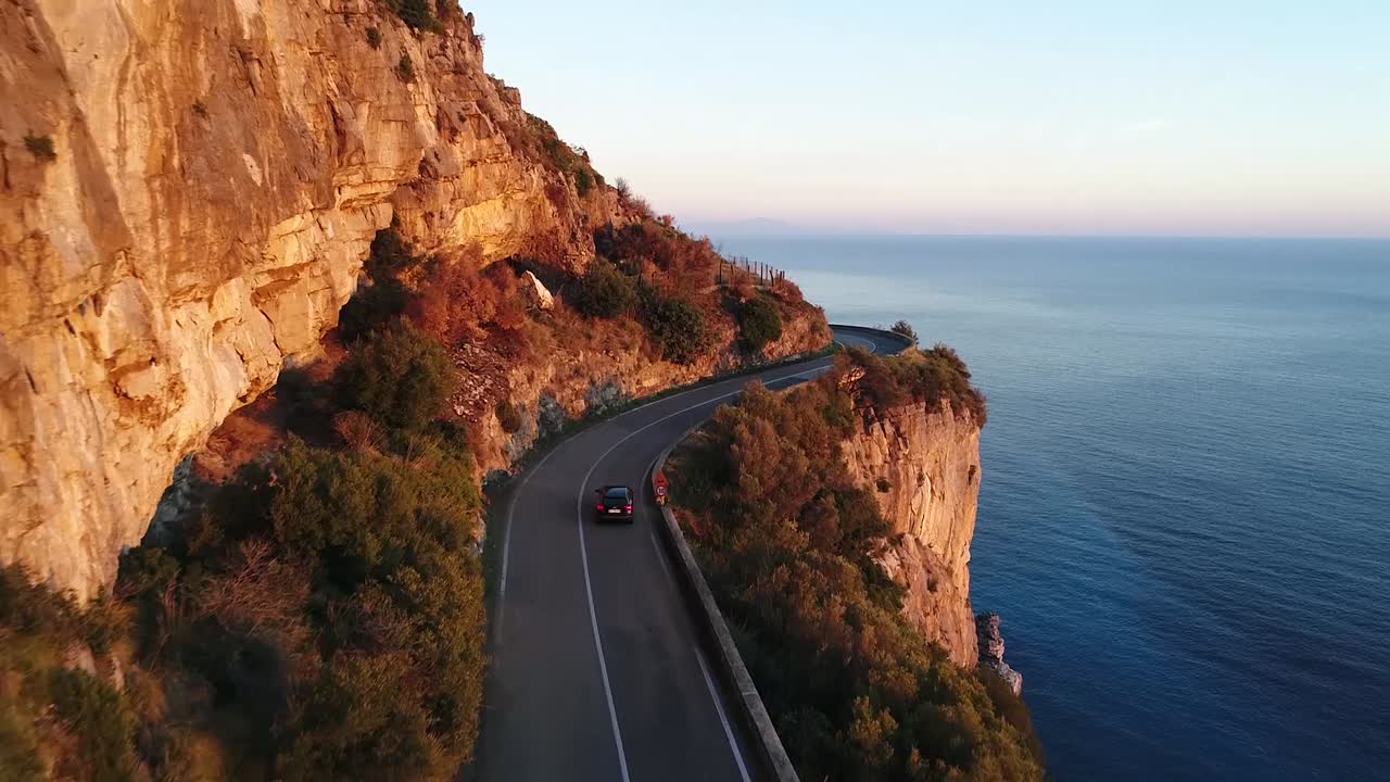 a car is driving in the beautiful amalfi coast in italy during the golden hour