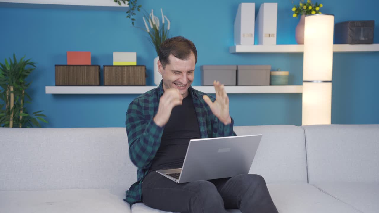 el hombre que usa una computadora portátil es feliz en casa, recibe buenas noticias, es feliz.