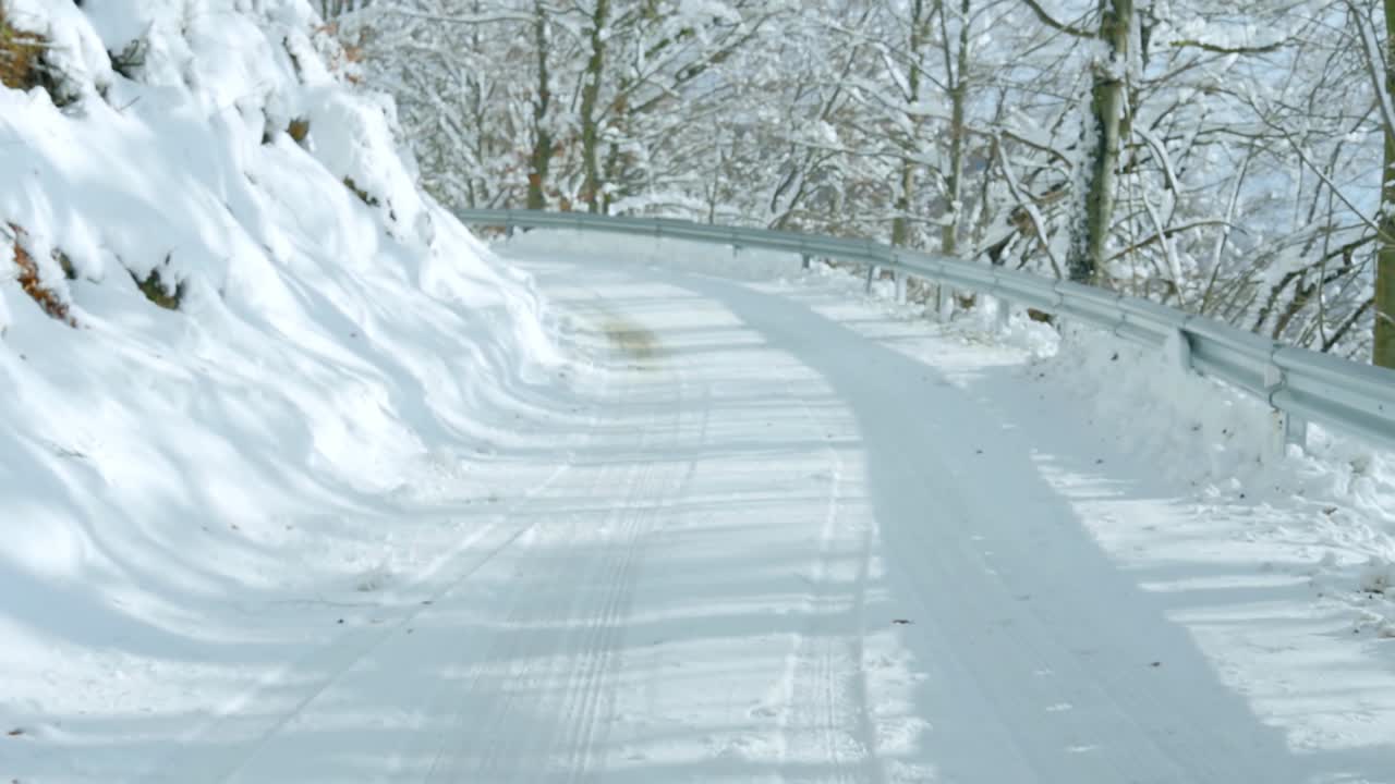 눈 덮힌 나무로 둘러싸인 눈 덮인 산길에서 운전