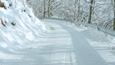 Driving-on-snowy-mountain-road,-surrounded-by-snow-covered-trees