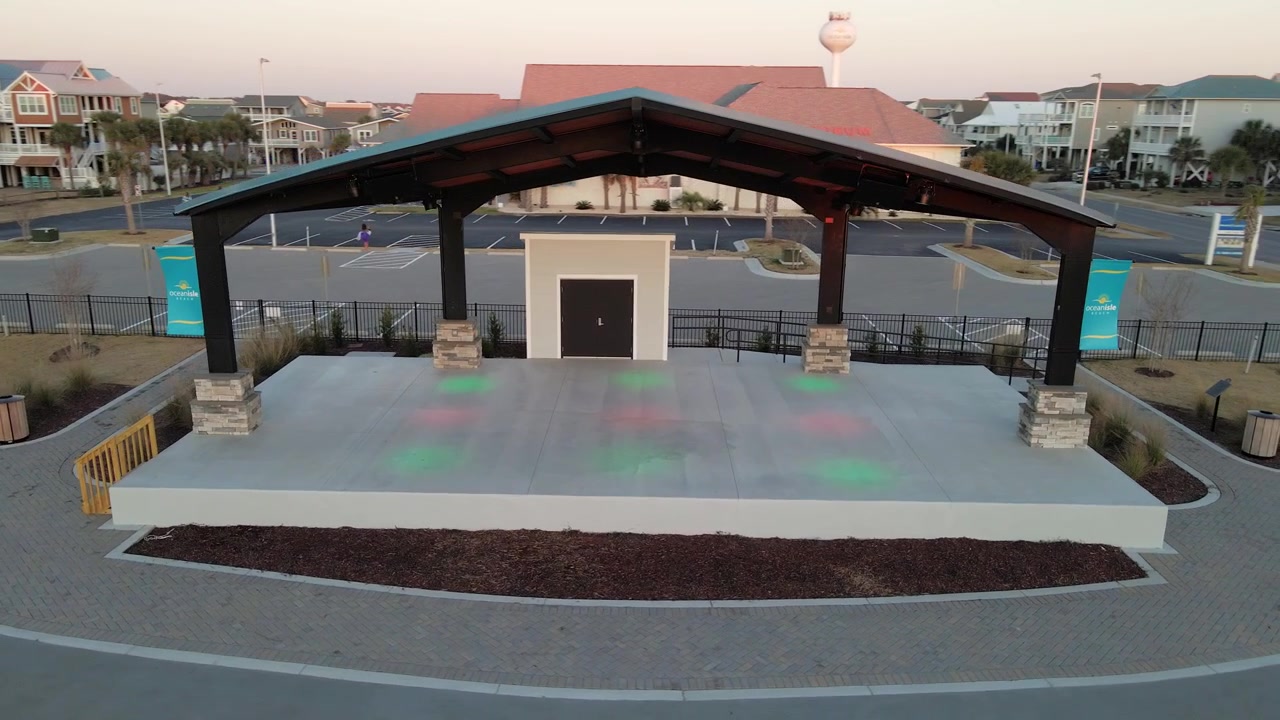 Aerial panning shot of empty outdoor stage with lighting spotlight preparing for music concert at night. Ocean Isle,America.