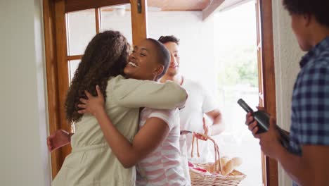 Group-of-diverse-male-and-female-friends-welcoming-each-other-in-doorway