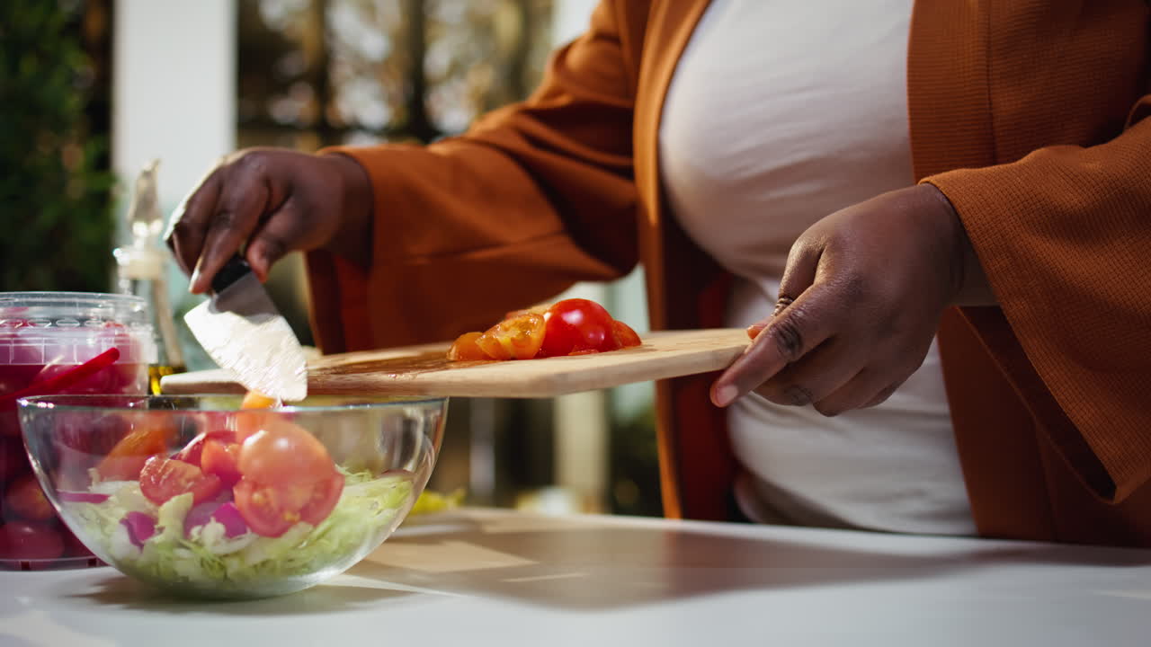 Food vlogger che taglia pomodorini, ricetta insalata al bancone.