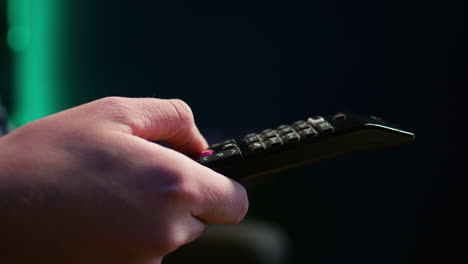 un hombre en el sofá usando el control remoto cambiando los canales en la televisión