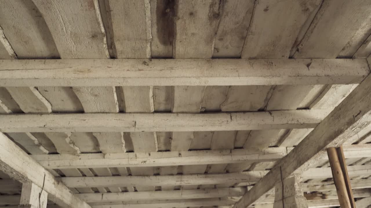 Tilt up shot of wooden ceiling revealing moldy leaking hole, handheld view
