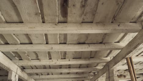 tilt up shot of wooden ceiling revealing moldy leaking hole, handheld view