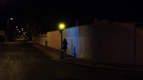 Mujer-Joven-Asustada-Mirando-Hacia-Atrás-Mientras-Camina-Sola-En-La-Calle-Oscura-Por-La-Noche