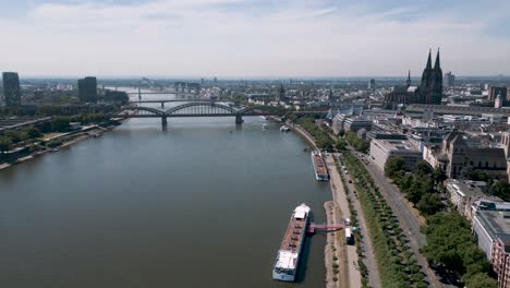 cologne, north rhine-westphalia, germany - panorama aerial bird drone flight towards the köln dom and city center along the rhein river with passenger ships - establishing shot