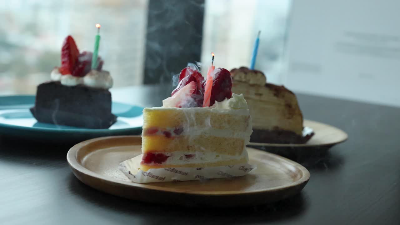 A hand extinguishes a candle on strawberry shortcake, natural daylight, close-up, shallow focus