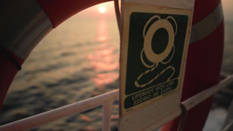 life buoy on the foreground with the sea and sunset on the background while focus racking on a cruise ship in the mediterranean sea, greece