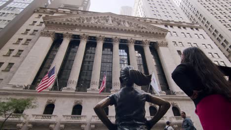 tourist admiring the fearless girl statue outside the new york stock exchange in manhattan