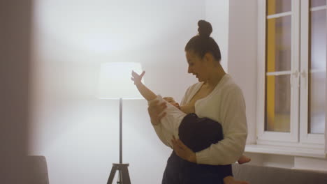 Young-Mother-Breastfeeding-And-Cuddling-Her-Baby-Boy-While-Standing-In-The-Living-Room-At-Home