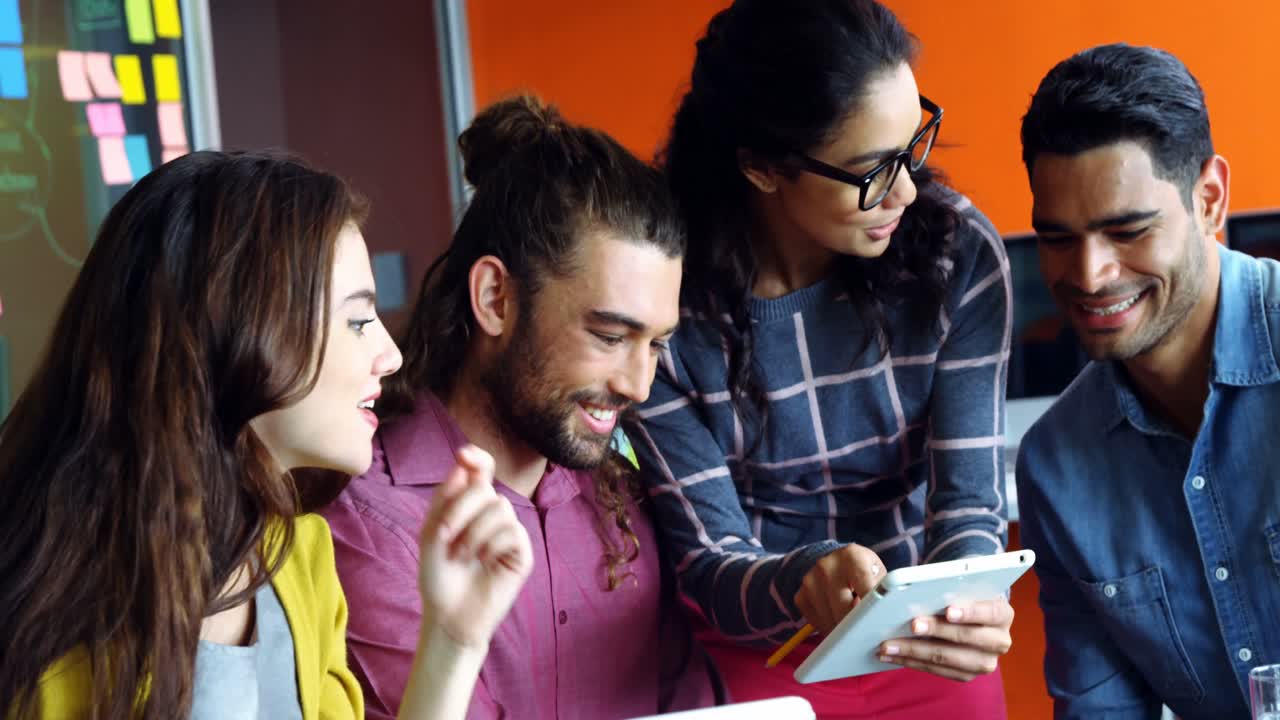 diseñadores gráficos sonrientes discutiendo sobre la tableta digital en una reunión