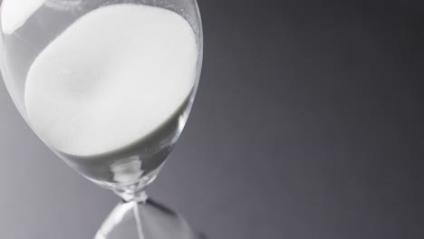 video of close up of hourglass with sand pouring, copy space on black background