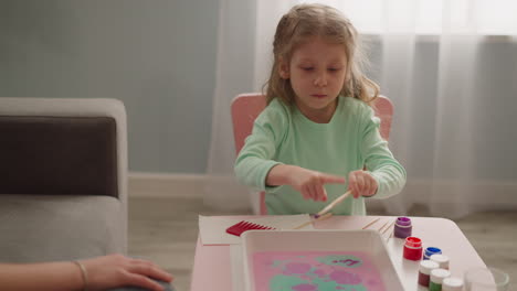 adorable little girl makes colorful pattern on water surface