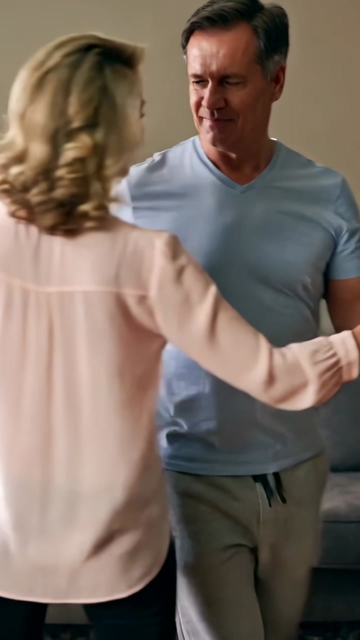 Vertical video: Clasping hands guiding couple dancing at home, sofa, sharing romantic moment