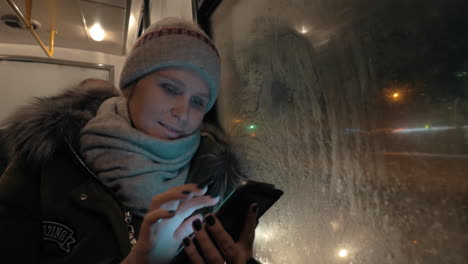 woman using cellphone during bus ride in winter evening