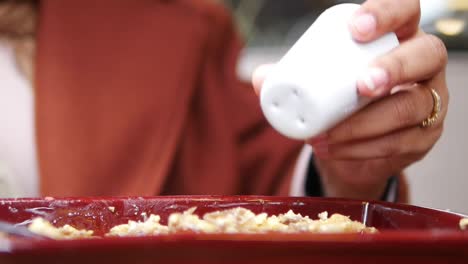 woman adding salt to a dish