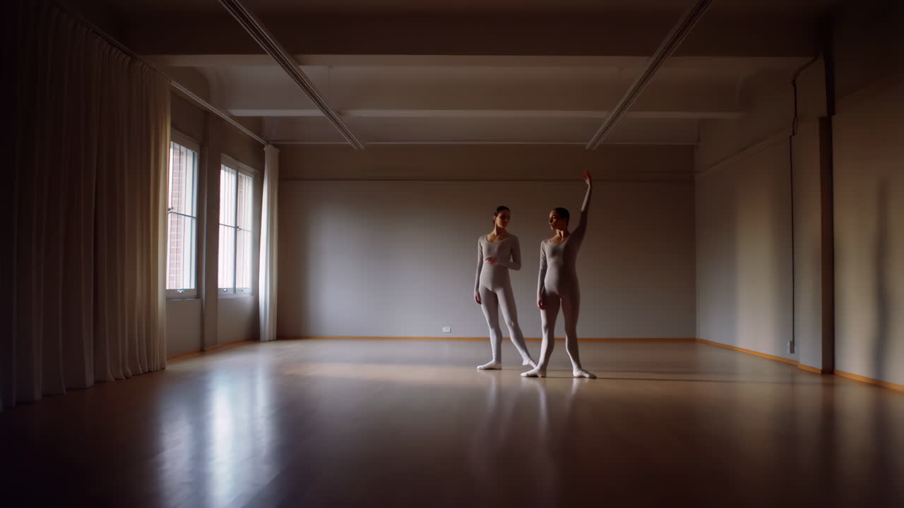 Two dancers practicing ballet in a spacious studio