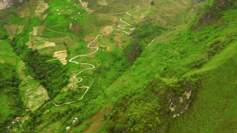 Toma-Aérea-Ascendente-Sobre-Una-Montaña-Que-Revela-Un-Camino-Sinuoso-Cortado-En-Las-Montañas-Del-Hermoso-Paso-Ma-Pi-Leng-En-El-Norte-De-Vietnam