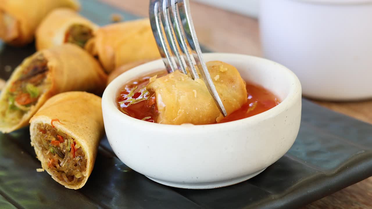 Dipping a spring roll into sweet chili sauce