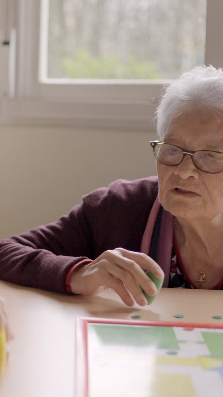 Women having fun playing Parcheesi board game in a geriatric