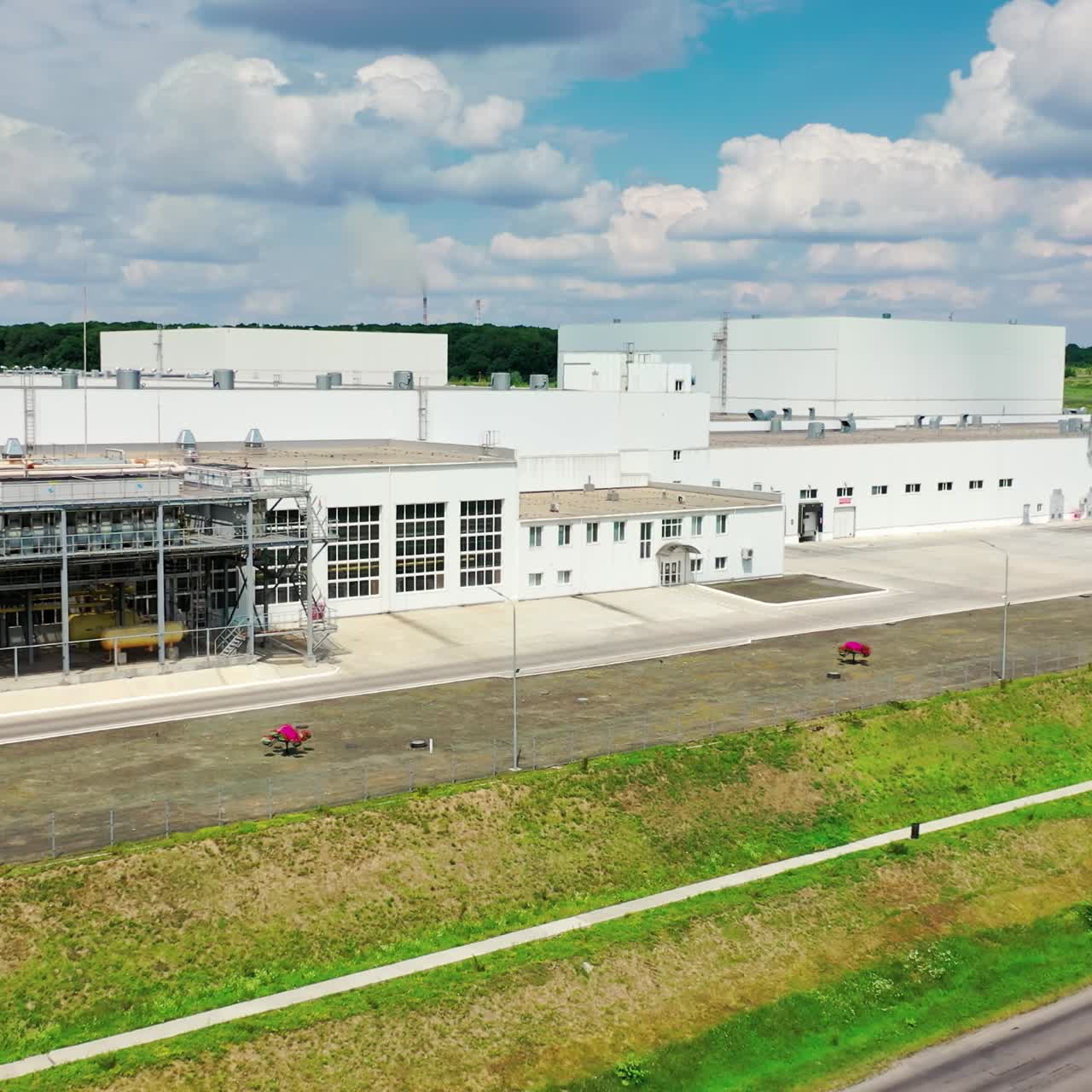 Contemporary industrial plant near the highway. White buildings of innovative factory on green nature background. Top down