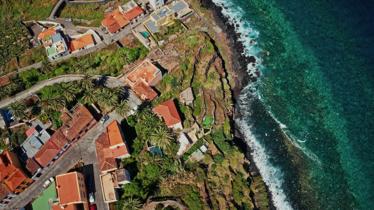 Aerial drone shot over the coastline of La Palma, Canary Islands, Spain. High view of the turquoise ocean, rugged coastline, banana plantations and the small local town. Summer holidays destination.